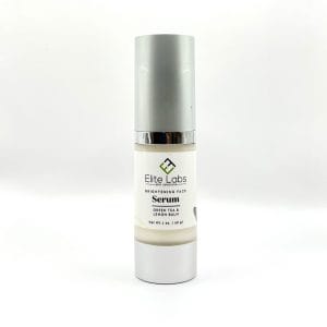 A bottle of Brightening Face Serum by Elite Labs, featuring green tea and lemon balm, placed on a white background.